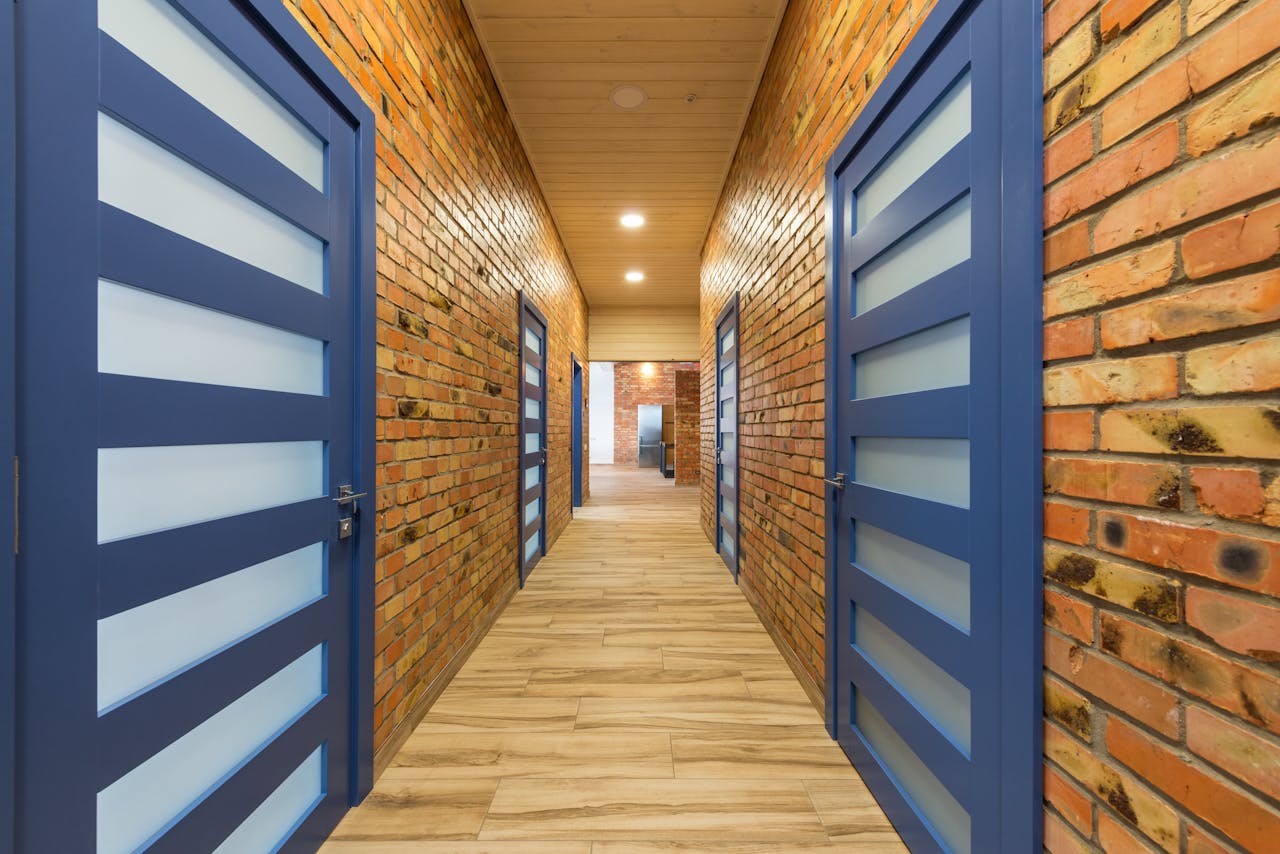Bright hallway with brick walls and striking blue doors creating a modern atmosphere.